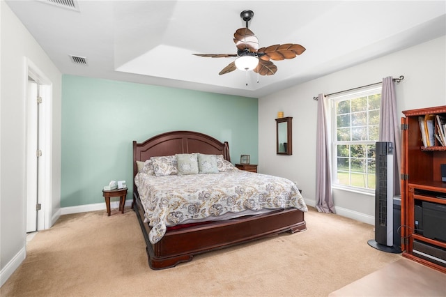 bedroom with baseboards, visible vents, a ceiling fan, and light carpet