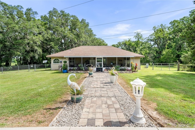 view of front of property with a sunroom, a fenced backyard, and a front yard
