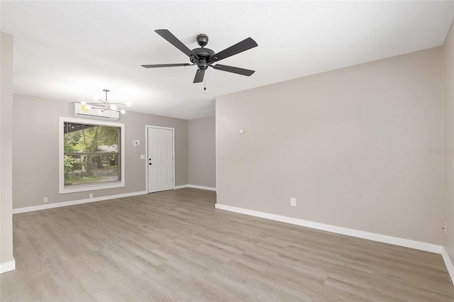 unfurnished room featuring ceiling fan with notable chandelier and light wood-type flooring