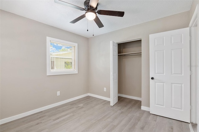 unfurnished bedroom featuring ceiling fan, a closet, light hardwood / wood-style flooring, and a textured ceiling