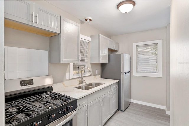 kitchen featuring white cabinetry, appliances with stainless steel finishes, sink, and light hardwood / wood-style flooring