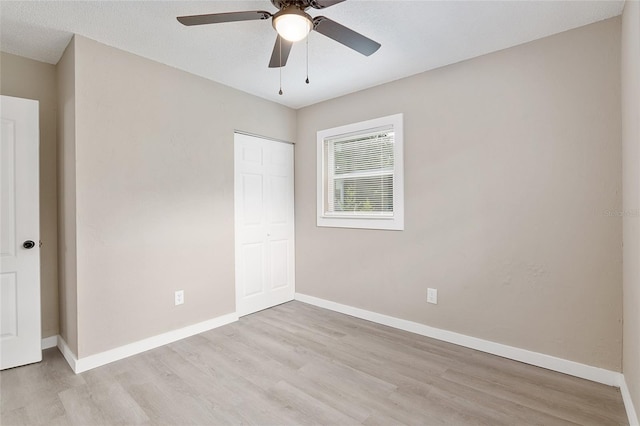 unfurnished bedroom with ceiling fan, light wood-type flooring, and a closet