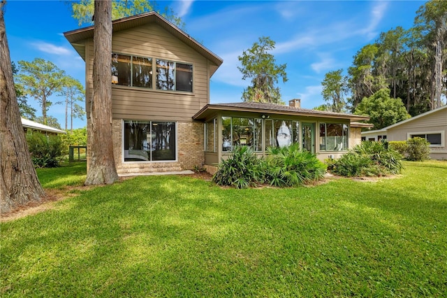 rear view of property with a sunroom and a lawn