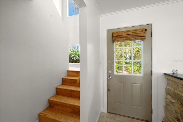 doorway to outside with plenty of natural light, crown molding, and light tile flooring