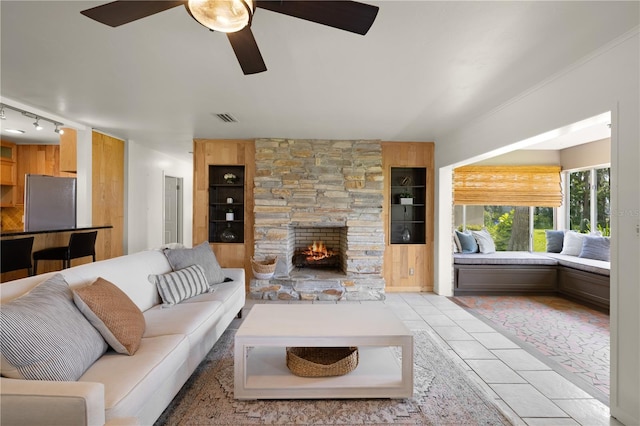 living room featuring ceiling fan, a fireplace, light tile flooring, built in features, and track lighting