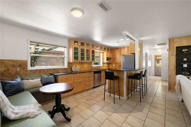 kitchen with stainless steel appliances, track lighting, tasteful backsplash, and light tile floors