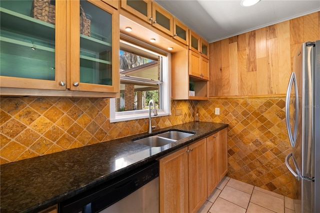 kitchen with backsplash, dark stone countertops, appliances with stainless steel finishes, sink, and light tile floors