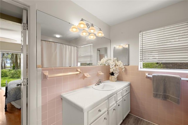 bathroom with tile walls, vanity with extensive cabinet space, and wood-type flooring