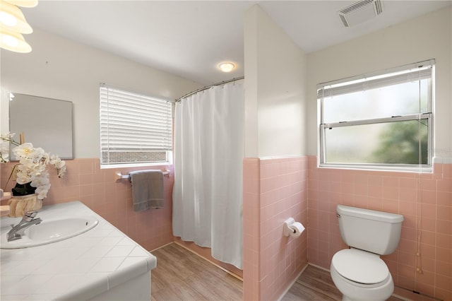 bathroom featuring hardwood / wood-style floors, tile walls, toilet, and vanity