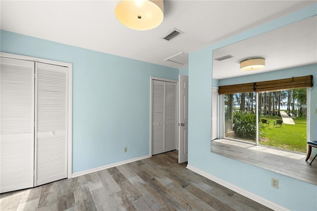 unfurnished bedroom featuring multiple closets and wood-type flooring