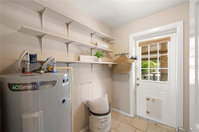 laundry room featuring light tile flooring and electric water heater