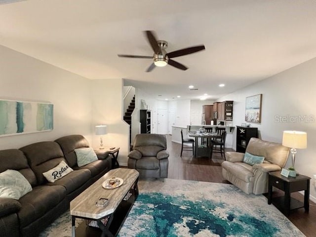 living room featuring dark wood-type flooring and ceiling fan