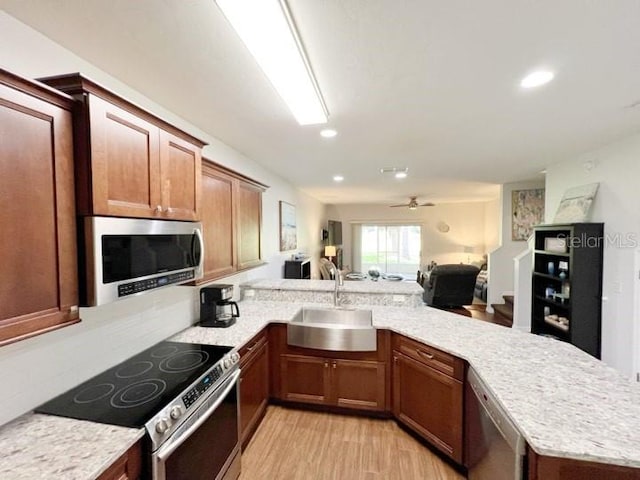 kitchen featuring sink, light wood-type flooring, kitchen peninsula, ceiling fan, and stainless steel appliances