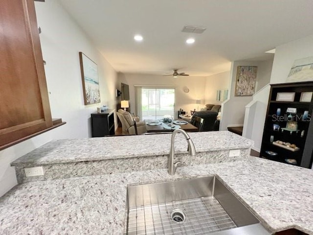 kitchen featuring sink, light stone countertops, and ceiling fan