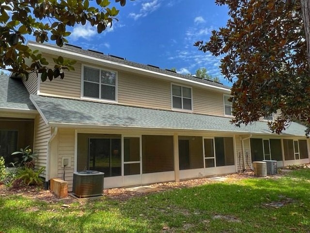 rear view of property featuring a sunroom, a yard, and central air condition unit