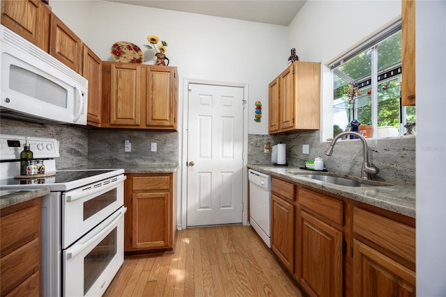 kitchen featuring light wood-type flooring, white appliances, tasteful backsplash, and sink