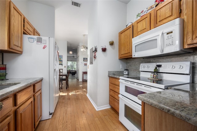 kitchen featuring white appliances, light hardwood / wood-style floors, ceiling fan, and dark stone countertops