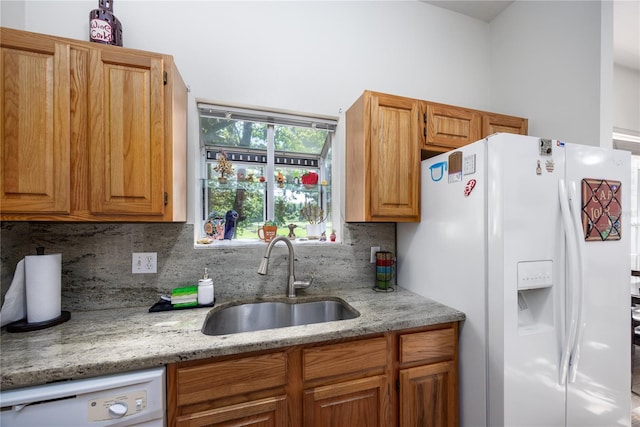 kitchen with light stone countertops, white appliances, tasteful backsplash, and sink