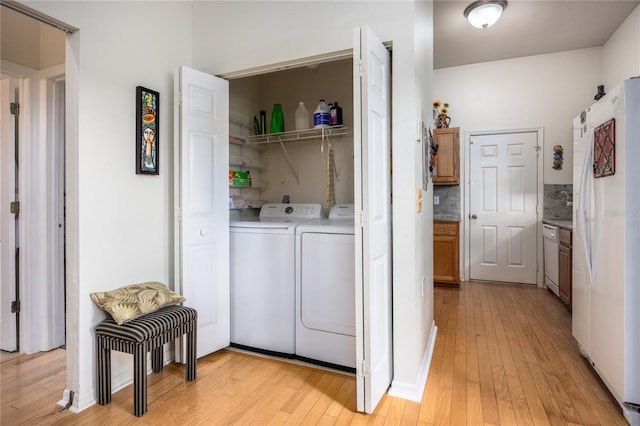 laundry room featuring washing machine and clothes dryer and light hardwood / wood-style flooring