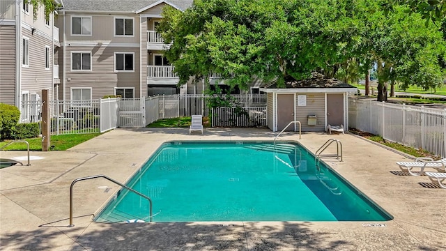 view of pool featuring a storage shed and a patio