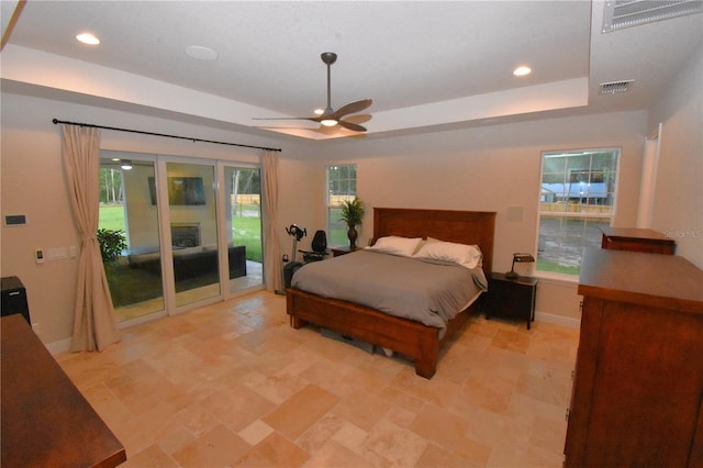 bedroom with ceiling fan, a tray ceiling, and access to outside