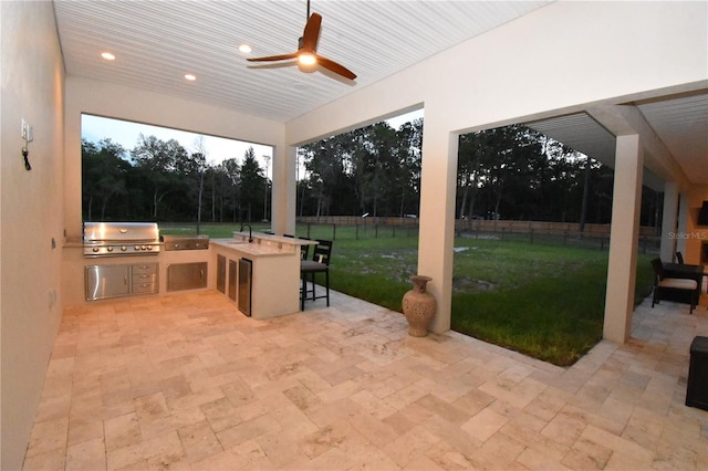 view of patio / terrace with area for grilling, a wet bar, ceiling fan, and exterior kitchen