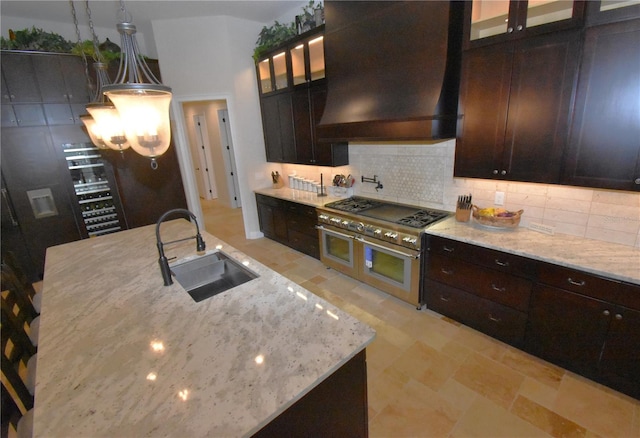 kitchen featuring pendant lighting, sink, light stone counters, tasteful backsplash, and custom range hood