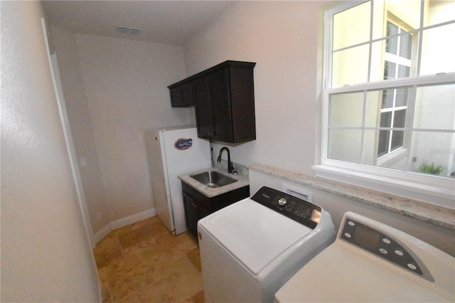 washroom featuring separate washer and dryer, sink, and cabinets