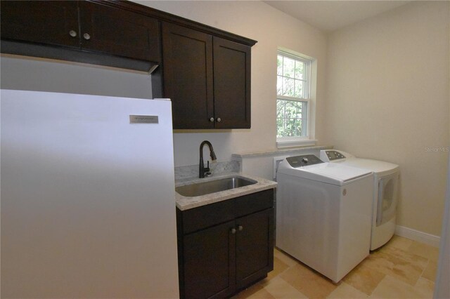 clothes washing area with cabinets, sink, and independent washer and dryer