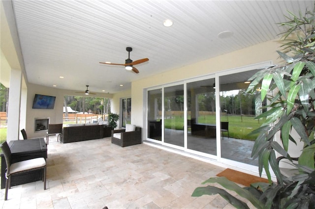 view of patio with an outdoor living space with a fireplace and ceiling fan