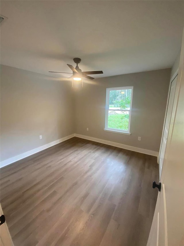 unfurnished room with ceiling fan and dark wood-type flooring