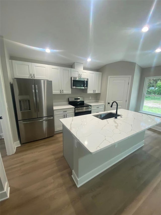 kitchen with appliances with stainless steel finishes, light stone counters, sink, a center island with sink, and white cabinets