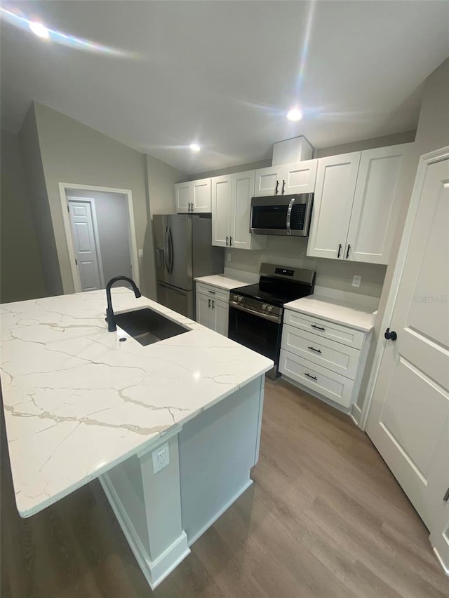 kitchen featuring light stone counters, stainless steel appliances, white cabinetry, and sink