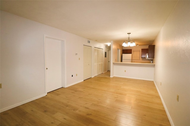 unfurnished living room with a chandelier and light hardwood / wood-style flooring