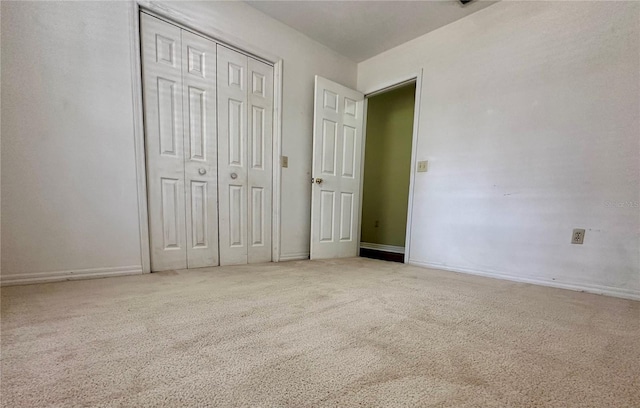 unfurnished bedroom featuring light carpet and a closet