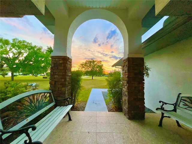 patio terrace at dusk featuring a lawn