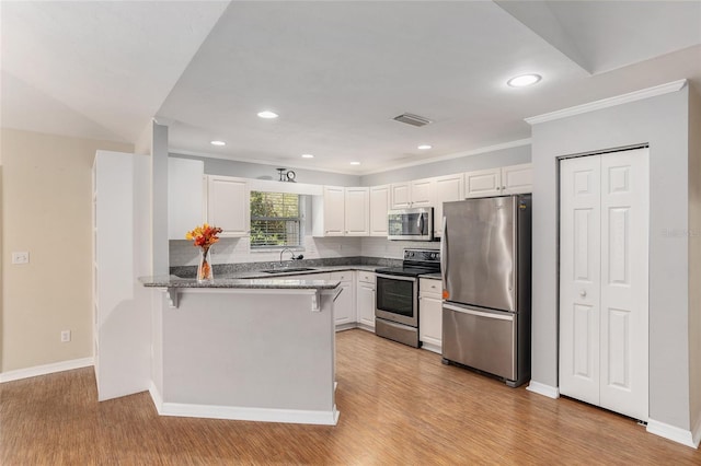 kitchen featuring kitchen peninsula, white cabinetry, sink, and stainless steel appliances