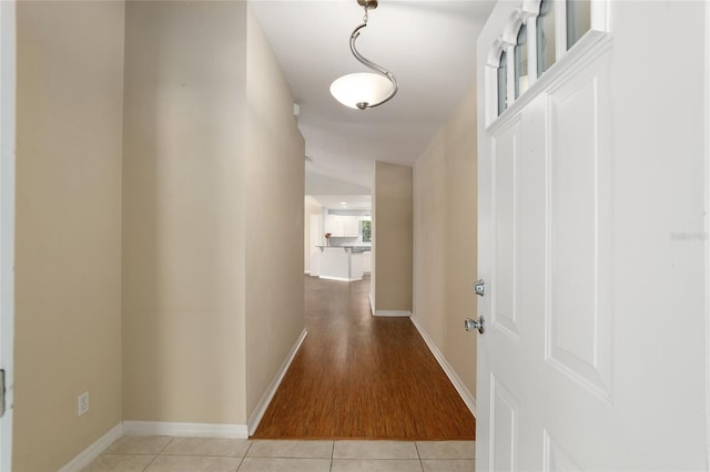 corridor featuring lofted ceiling and light tile patterned flooring