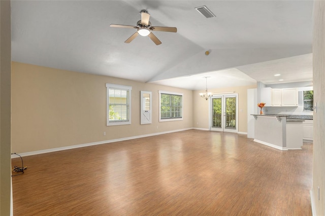 unfurnished living room with light wood-type flooring, ceiling fan with notable chandelier, and vaulted ceiling