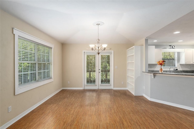 unfurnished dining area with light wood-type flooring, an inviting chandelier, lofted ceiling, and sink