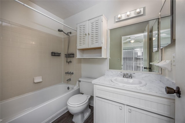 full bathroom featuring ceiling fan, vanity, toilet, and tiled shower / bath