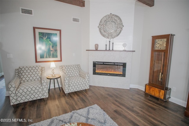 living area with high vaulted ceiling, beamed ceiling, a tile fireplace, and dark hardwood / wood-style floors