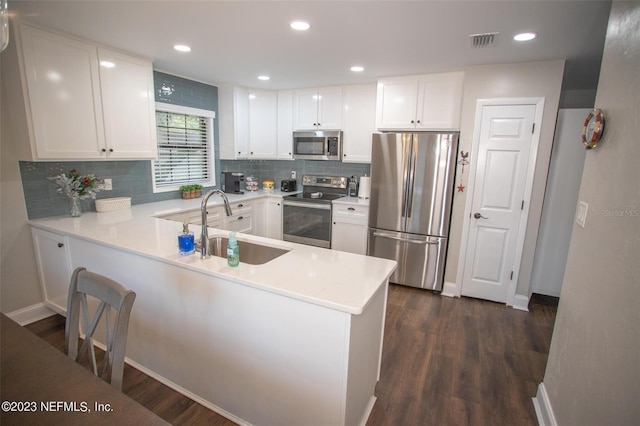 kitchen with dark hardwood / wood-style flooring, kitchen peninsula, and appliances with stainless steel finishes