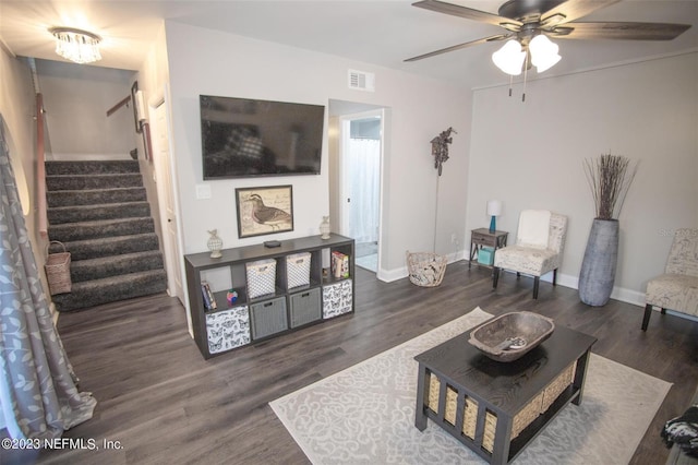 living area featuring a ceiling fan, visible vents, baseboards, stairway, and dark wood finished floors