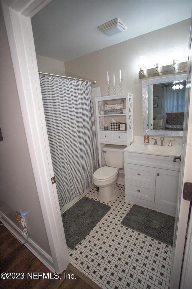 bathroom with connected bathroom, toilet, a shower with shower curtain, visible vents, and vanity