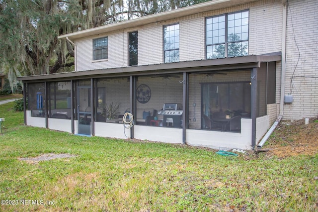 rear view of house with a sunroom and a lawn