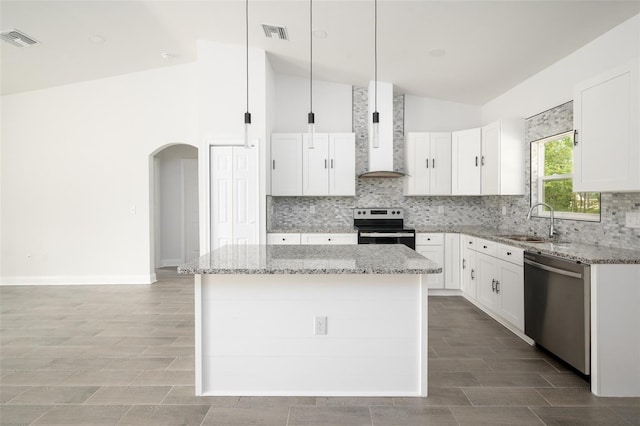 kitchen with sink, appliances with stainless steel finishes, white cabinetry, a center island, and wall chimney exhaust hood