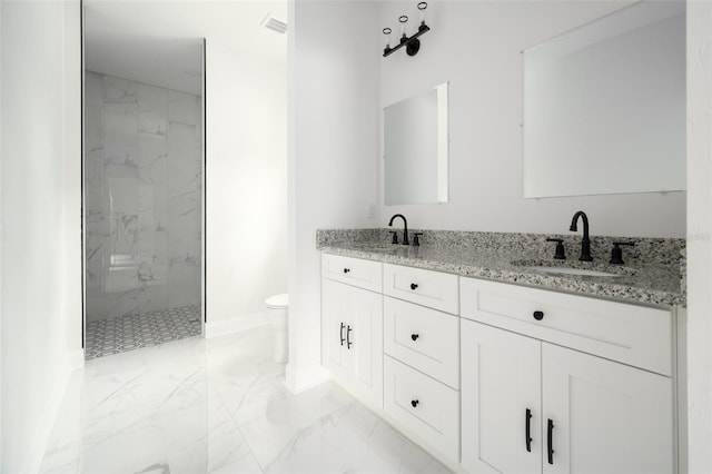 bathroom featuring vanity, a tile shower, and toilet