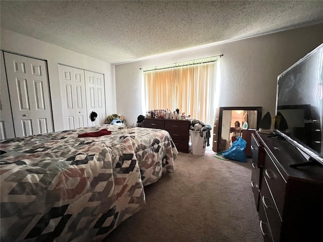 bedroom with carpet, a textured ceiling, and multiple closets