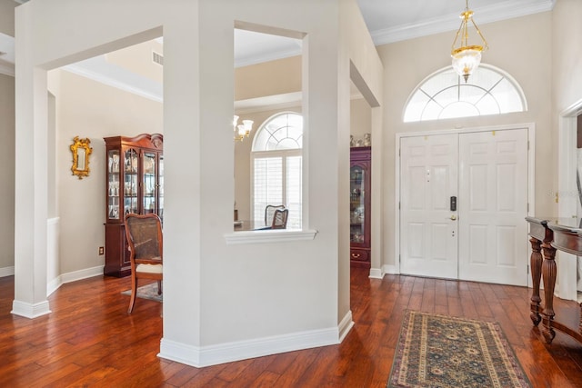 foyer featuring dark hardwood / wood-style flooring, an inviting chandelier, and crown molding